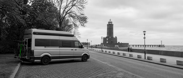 Latarnia i port w Kołobrzegu z kamperem oraz jednym zielonym akcentem linki na bagażniku kampera